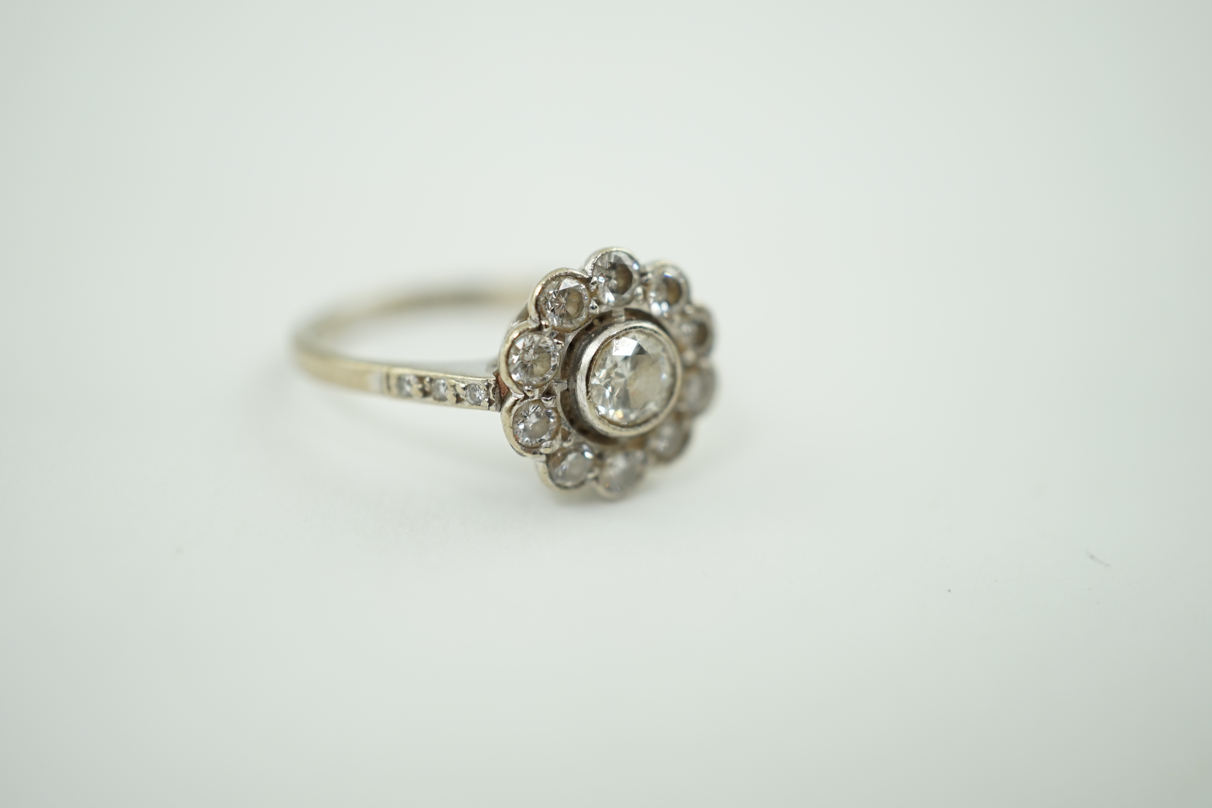 A mid 20th century 18ct white gold and eleven stone diamond set flower head cluster ring